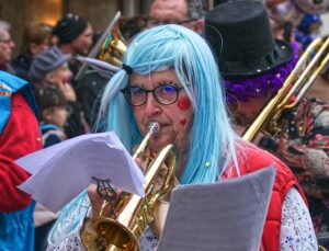 woman in white hair wearing red dress playing trumpet