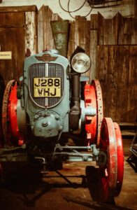 an old blue and red tractor sitting in a barn