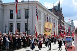 Festive parade with traditional costumes and norwegian flags.